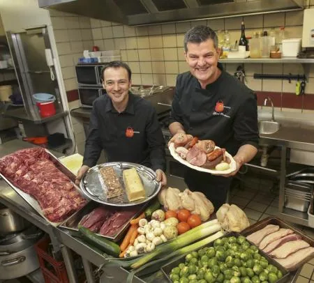 Les deux cuisiniers en cuisine, avec viandes, légumes et terrines