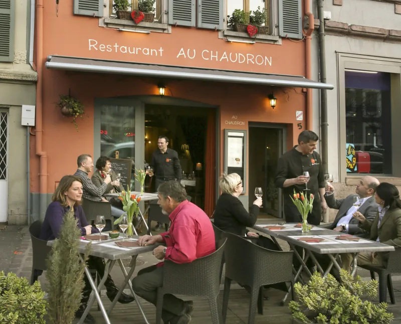 La façade saumon du restaurant Au Chaudron et sa terrasse, place du Marché aux Fruits